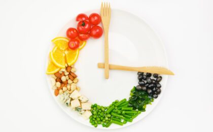 Colorful food and cutlery arranged in the form of a clock on a plate