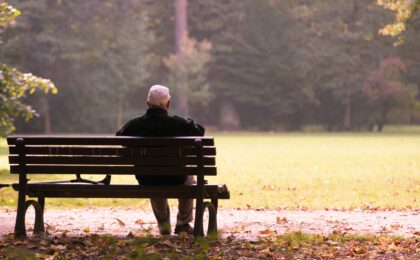 Old man sitting on a bench in autumn, autumn of life